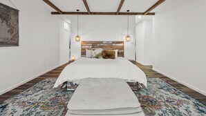 Une chambre avec un grand lit, des poutres en bois, une carte du monde et des tapis à motifs.
