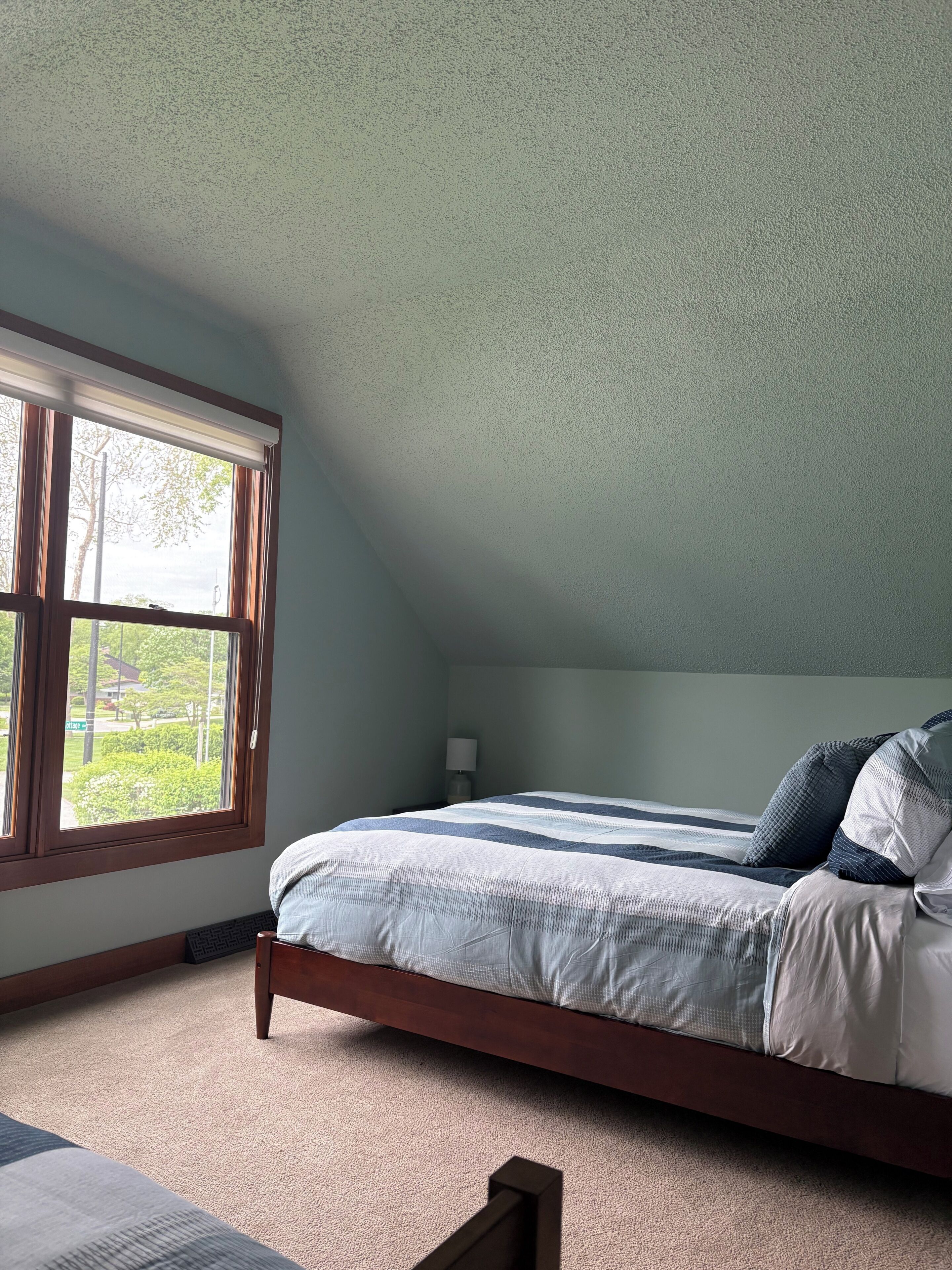 Une chambre à coucher avec un lit, une fenêtre et une table de chevet.