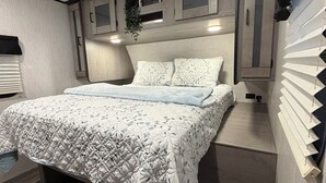 A modern bedroom with a bed, built-in cabinets, and a window with blinds.