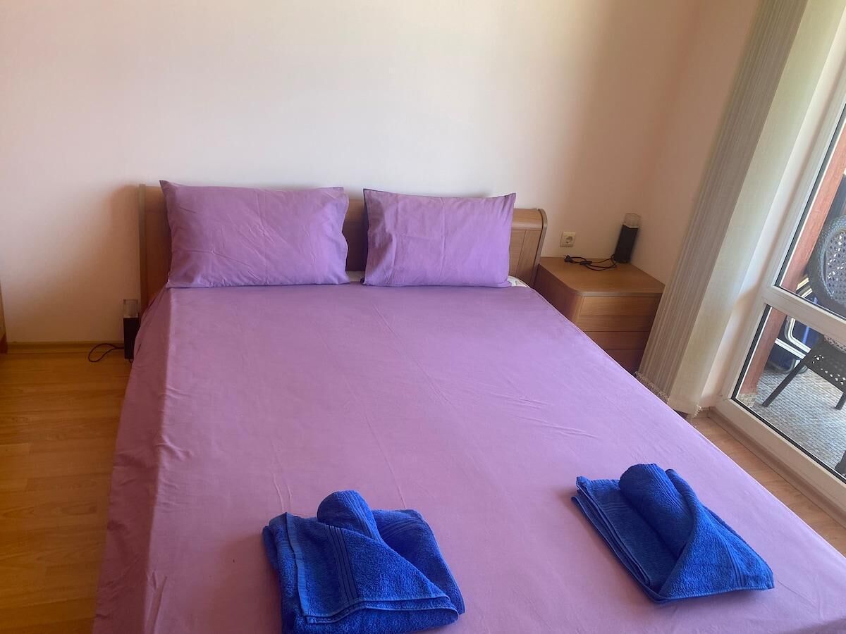 Una cama con ropa de cama morada, dos almohadas y dos toallas dobladas.