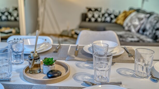 A dining table set with plates, glasses, cutlery, and a small plant centerpiece. - The Manchester City Haven (Manchester)
