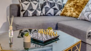 A chessboard on a glass coffee table with a plant and a reed diffuser. - The Manchester City Haven (Manchester)