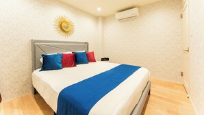 A neatly made bed with a blue and white bedspread, a grey headboard, and red and blue pillows. - Lrge New Luxury Home 1 Minute walk to Station 6 Min Ride to Namba Great for USJ (Osaka)