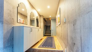 A hallway with a wooden floor, a set of stairs, and a row of shoes on the floor. - Lrge New Luxury Home 1 Minute walk to Station 6 Min Ride to Namba Great for USJ (Osaka)