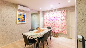 A dining area with a marble table, grey chairs, and a wall decorated with pink and white flowers. - Lrge New Luxury Home 1 Minute walk to Station 6 Min Ride to Namba Great for USJ (Osaka)