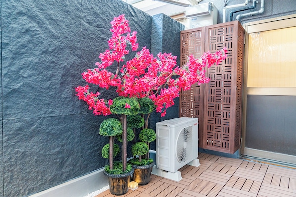 A modern indoor space with a stone wall, a decorative wooden screen, and a potted plant with pink flowers.