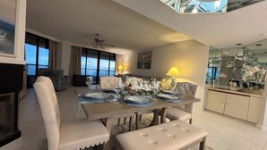 Ein Essbereich mit Tisch für vier Personen, einer Couch, einem Deckenventilator und Blick ins Freie.