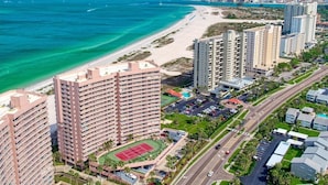 Ein Hochhaus-Hotel mit mehreren Etagen, einem Strand und einer Straße.