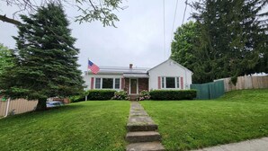 A single-story house with a front porch, a flag, and a well-maintained lawn. - ​Upstate Oasis: Moody Chic Interior & Summer Pool Fun (Carthage)