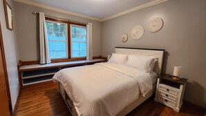 A bedroom with a bed, a nightstand, a window with a view, and decorative wall art. - ​Upstate Oasis: Moody Chic Interior & Summer Pool Fun (Carthage)