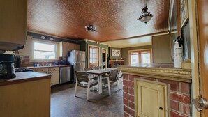 A kitchen with a dining area, a refrigerator, a stove, and a sink. - ​Upstate Oasis: Moody Chic Interior & Summer Pool Fun (Carthage)