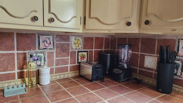 A kitchen with a brick backsplash, a toaster, a blender, and a pepper mill.