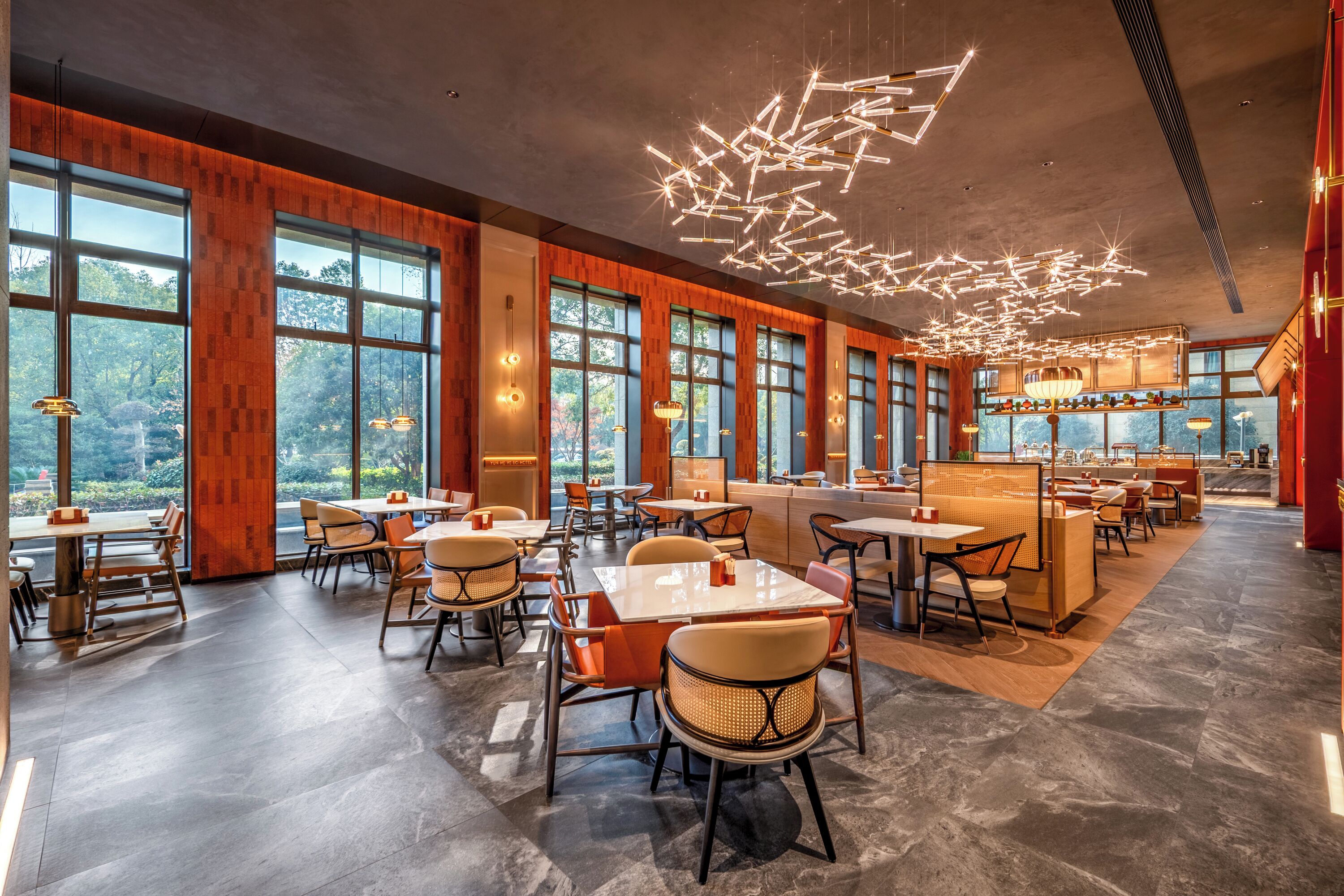 A spacious restaurant with high ceilings, large windows, and modern lighting fixtures.
