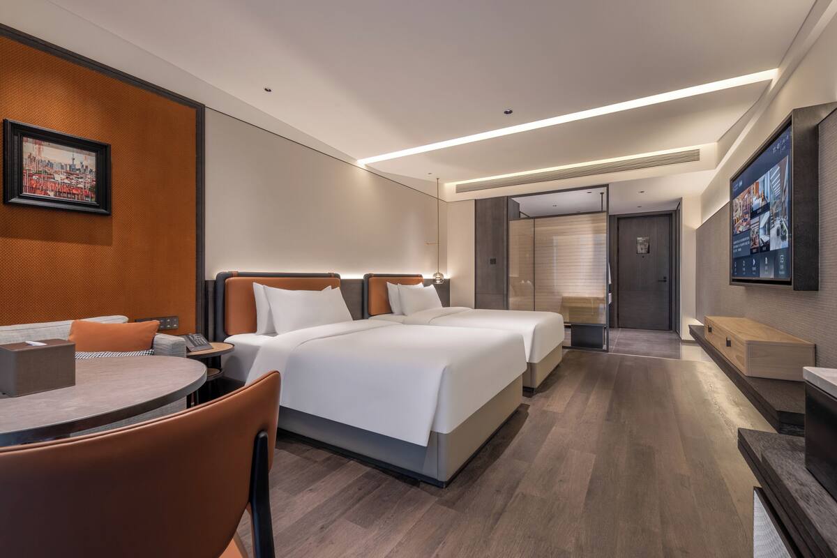 Une chambre d’hôtel avec deux lits, un coin repas, une télévision et une salle de bain.