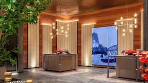 Een moderne receptie met een receptiebalie, een groot digitaal scherm en houten wandbekleding.