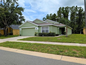 A single-story house with a green garage, a front yard with grass and a sidewalk, and a tree to the left. - Sandy`s Sanctuary - Conservation View - South-West Facing Pool (Davenport)