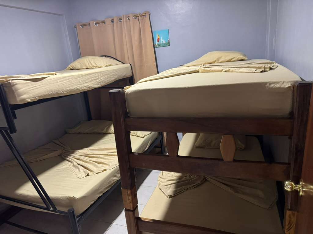 A room with bunk beds, a curtain, and a small picture on the wall.