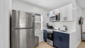 A modern kitchen with stainless steel appliances, white cabinets, and a blue countertop. - 3 Miles to Atlantic Ave - The Delray Chic Cottage (Delray Beach)