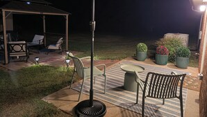 Eine Terrasse im Freien mit überdachtem Sitzbereich, einem Tisch und Kübelpflanzen.