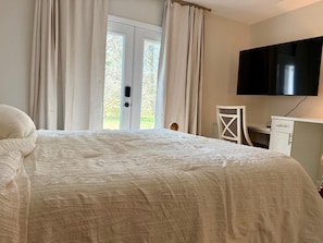 Un dormitorio con cama, escritorio, silla y televisor.