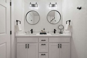 Une salle de bain avec deux lavabos, deux miroirs et un meuble-lavabo blanc doté de tiroirs.