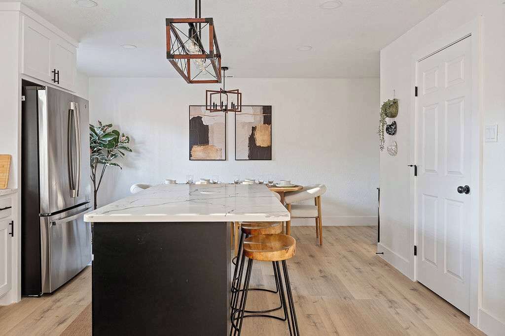 A modern kitchen with a central island, stainless steel appliances, and a hanging light fixture.