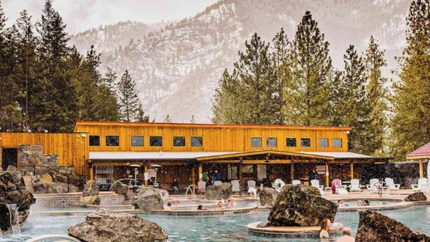 Eine Holzhütte mit Poolbereich, mehreren Whirlpools und großen Felsen.