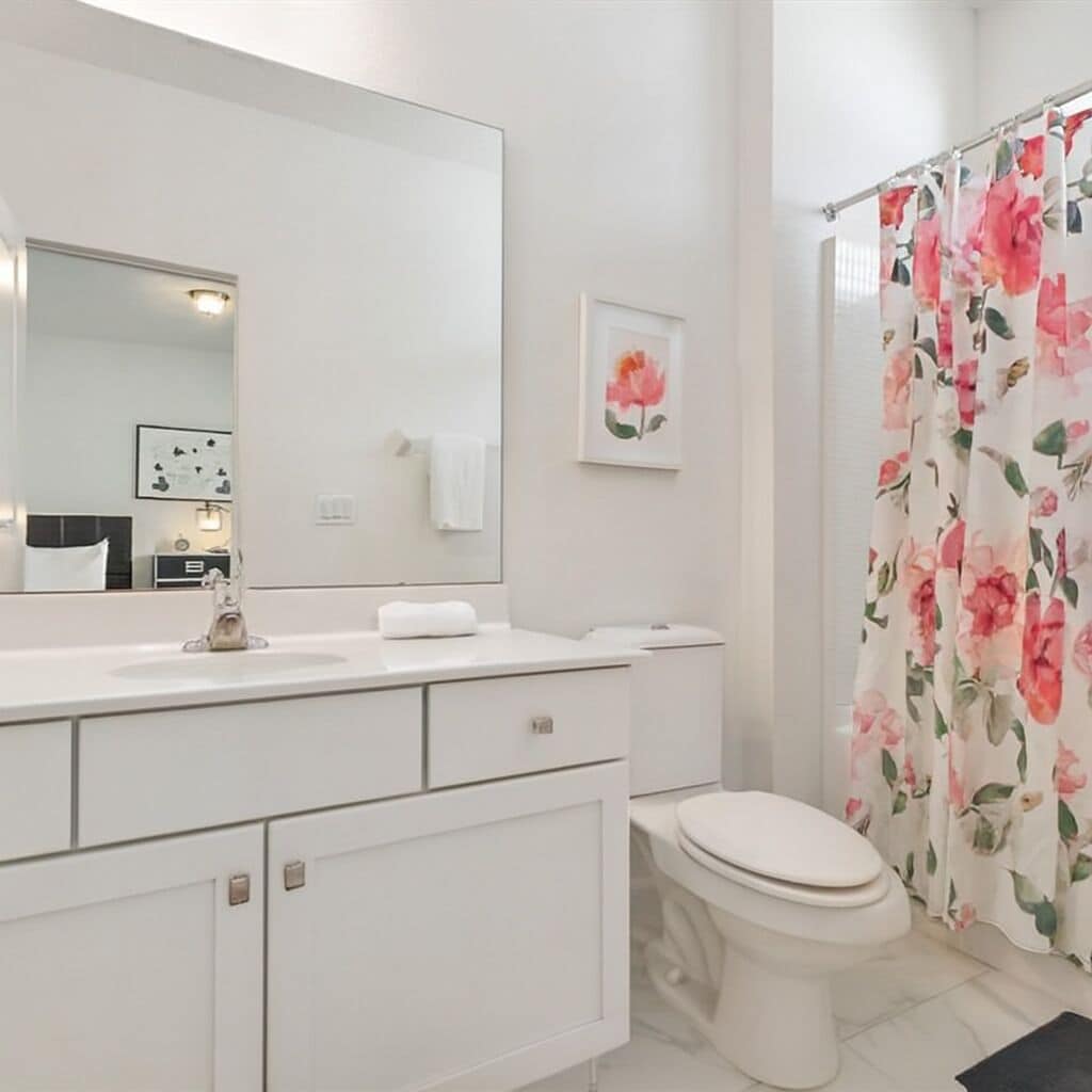 A bathroom with a white sink, mirror, and toilet.