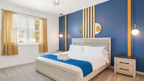 A hotel room with a bed, a nightstand, a wall with vertical stripes, and a window with curtains.