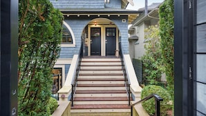 Un escalier menant à une maison à l’extérieur bleu foncé, avec une porte noire et un petit porche.