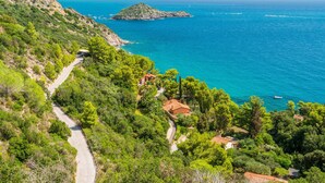 Une route côtière sinueuse qui traverse un paysage verdoyant, avec des maisons et une vue sur la mer.