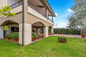 A two-story building with a covered patio area, potted plants, and a well-maintained lawn. - Villa Adriana Capalbio with A/C, BBQ and Parking, Capalbio, Italy (Capalbio)