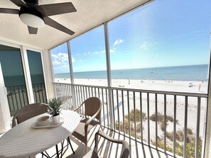 Ein Balkon mit Blick auf den Strand, Korbmöbel und einem Deckenventilator.