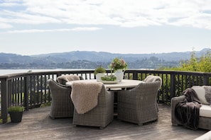 A deck with wicker furniture, a table, and potted plants. - Luxury Tiburon Retreat • Golden Gate Bridge / Bay Views from All 5 King Bedrooms (Tiburon)