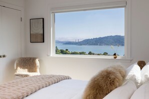 A bedroom with a large window offering a view of a bridge and hills. - Luxury Tiburon Retreat • Golden Gate Bridge / Bay Views from All 5 King Bedrooms (Tiburon)