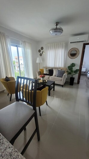 A modern living room with a sofa, chairs, a coffee table, and a dining area. - Elegant Pool-view Apartment Near Punta Cana Beach (Punta Cana)