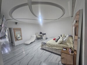 A modern bedroom with a bed, a desk, a chair, and a mirror.
