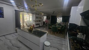 Eine moderne Küche mit Kochinsel, einem Essbereich mit grünen Stühlen und einer Insel mit Mülleimer.
