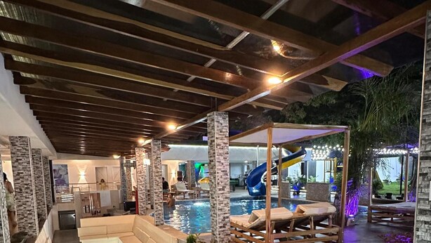 Ein überdachter Außenbereich mit Pool, Liegestühlen und einer Rutsche.
