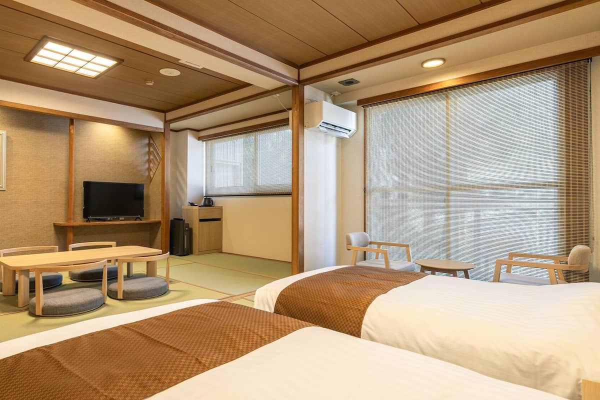 Une chambre d’hôtel avec des tatamis, une télévision, un bureau et un lit.