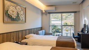 Une chambre d’hôtel avec deux lits, un tableau, un bureau avec un ordinateur et un balcon avec des chaises.