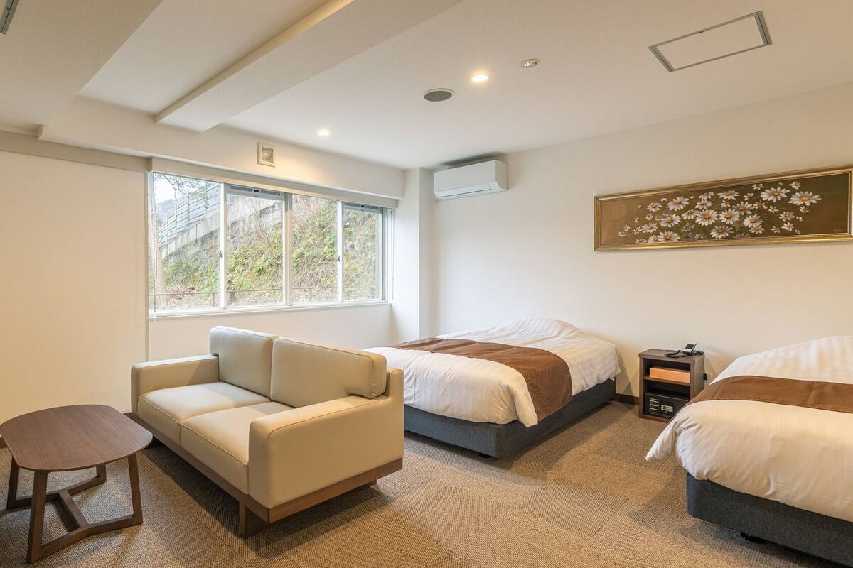 Une chambre d’hôtel avec un canapé, un lit, une petite table et un tableau au mur.