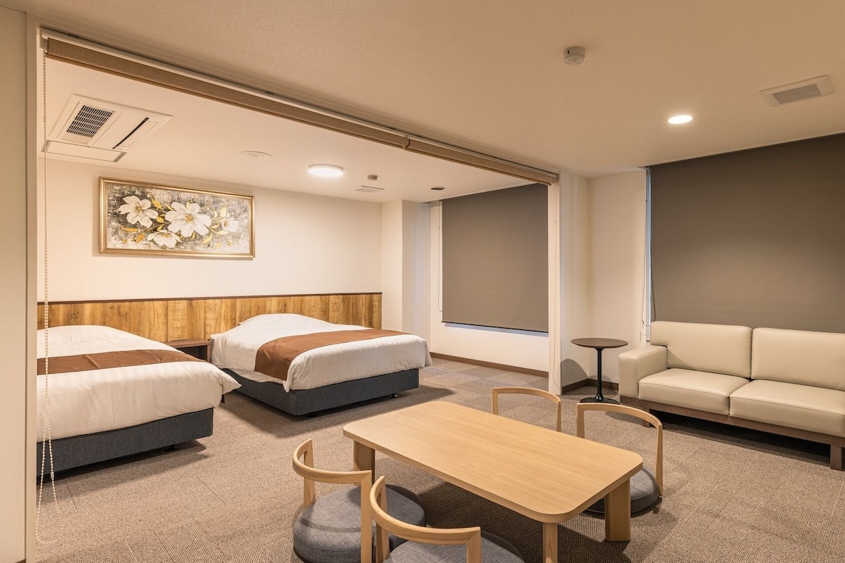 Une chambre d’hôtel avec deux lits, un canapé, une table et un téléviseur.