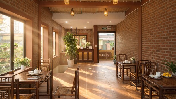 Un restaurant aux murs de briques, aux tables en bois et aux luminaires suspendus.
