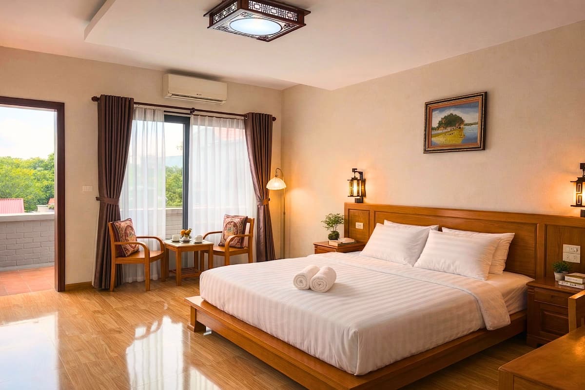 Habitación de hotel con una cama grande, un escritorio con sillas, un balcón con cortinas y un cuadro en la pared.