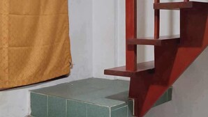 A staircase with green steps leading to a landing, a red handrail, and a yellow curtain on the wall.