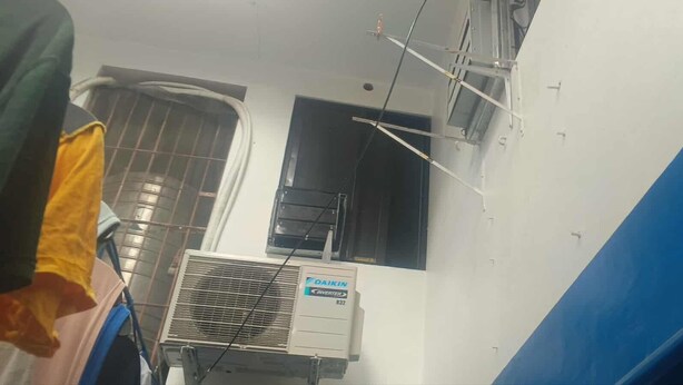 A room with a window, an air conditioning unit, and a blue wall.
