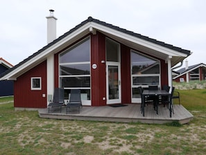Ein modernes Haus mit Terrasse, großen Fenstern und Schornstein.