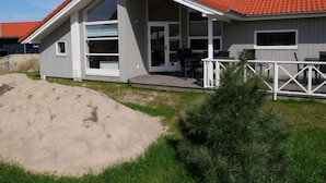 Ein modernes Haus mit rotem Ziegeldach, großen Fenstern und einer Terrasse.