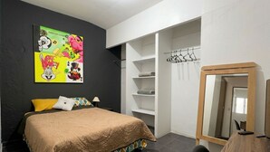 A bedroom with a bed, a wardrobe, a mirror, and a wall with a colorful poster. - Room with private bathroom in providencia (Guadalajara)